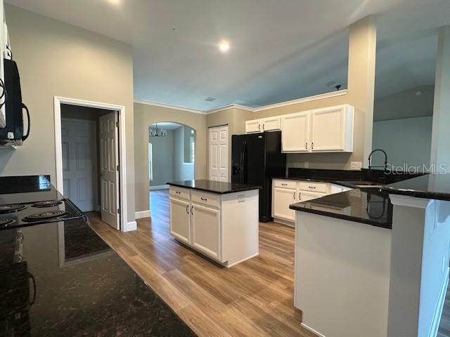 9934 SE 64th Ave, Belleview, FL 34420 - kitchen featuring white cabinets, arched walkways, a sink, a peninsula, and black appliances