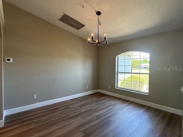 9934 SE 64th Ave, Belleview, FL 34420 - unfurnished room featuring a notable chandelier, dark wood-style flooring, baseboards, and a textured ceiling