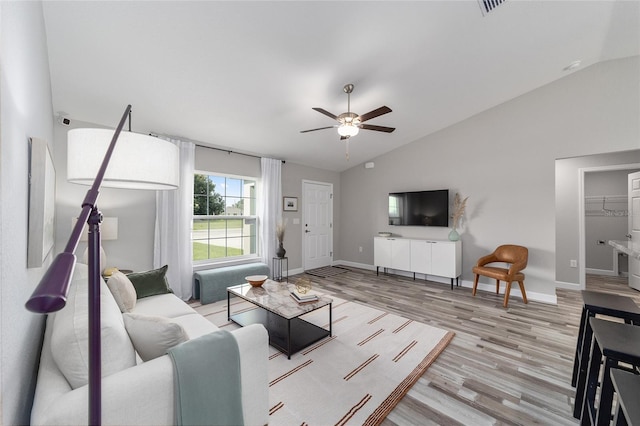 living area with baseboards, light wood-type flooring, vaulted ceiling, and ceiling fan