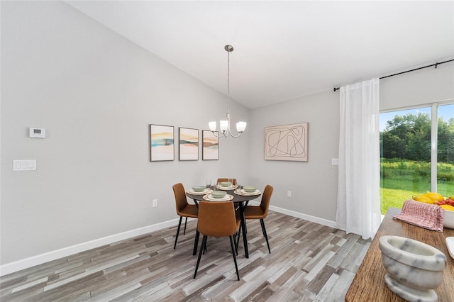 dining space with light wood-style floors, an inviting chandelier, baseboards, and vaulted ceiling