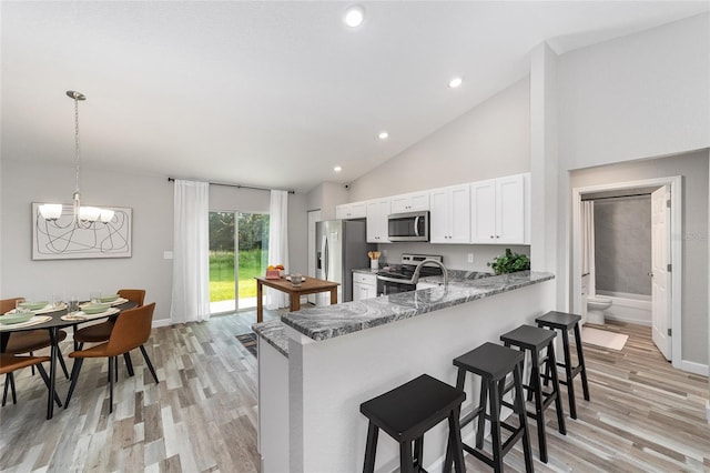 kitchen featuring an inviting chandelier, a kitchen breakfast bar, white cabinets, stainless steel appliances, and light wood finished floors