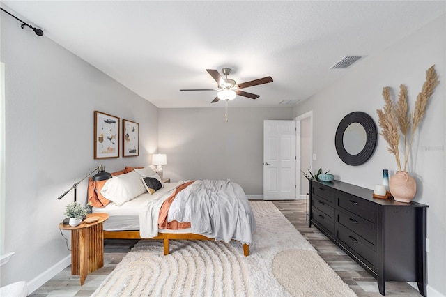 bedroom featuring visible vents, baseboards, a ceiling fan, and wood finished floors