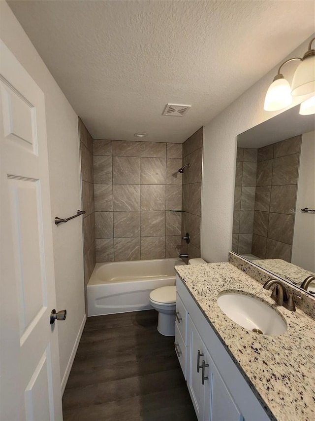 bathroom featuring toilet, a textured ceiling, shower / bath combination, wood finished floors, and visible vents