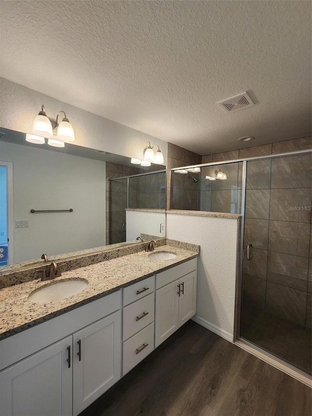 bathroom featuring a sink, a textured ceiling, wood finished floors, and visible vents