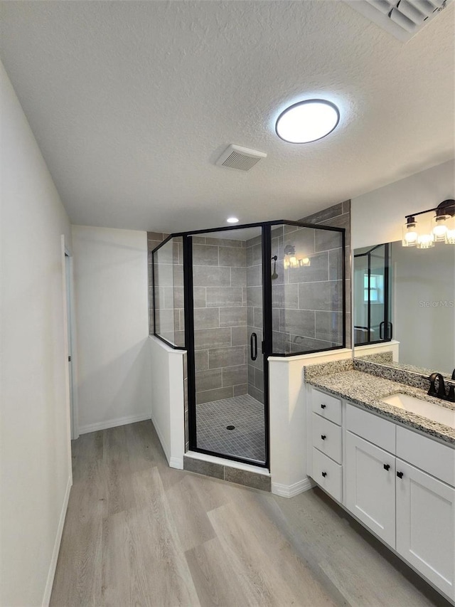 22764 SW Sea Cliff Ave, Dunnellon, FL 34431 - bathroom featuring wood finished floors, a textured ceiling, a shower stall, baseboards, and vanity
