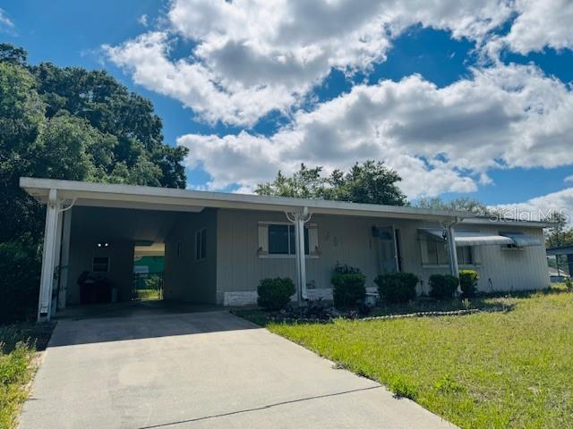 ranch-style house with concrete driveway, an attached carport, and a front lawn