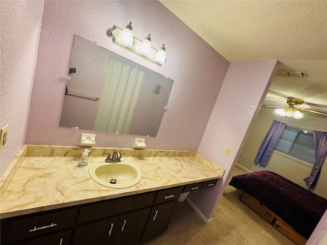 bathroom featuring a textured ceiling, a textured wall, a ceiling fan, and vanity