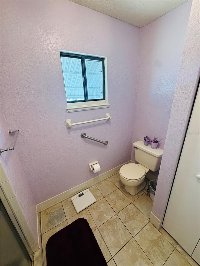bathroom featuring toilet, tile patterned flooring, and baseboards