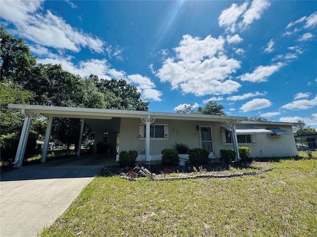 view of front facade with a carport, concrete driveway, and a front lawn