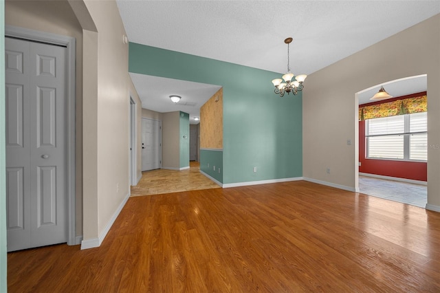 882 Tanglewood Pl, The Villages, FL 32162 - spare room featuring arched walkways, baseboards, an inviting chandelier, and wood finished floors