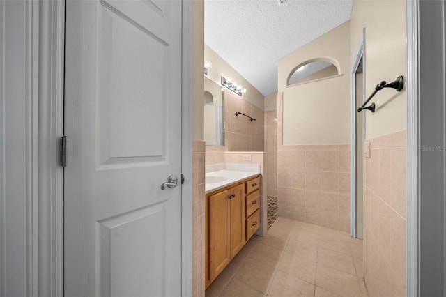 882 Tanglewood Pl, The Villages, FL 32162 - full bath featuring a tile shower, a textured ceiling, vanity, tile walls, and tile patterned floors