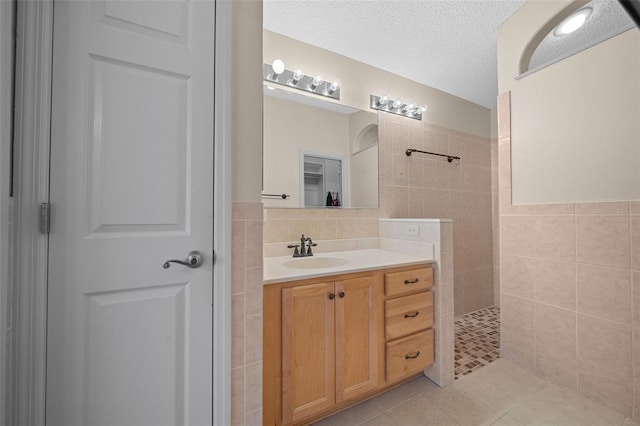 882 Tanglewood Pl, The Villages, FL 32162 - bathroom featuring walk in shower, tile walls, a textured ceiling, vanity, and tile patterned floors