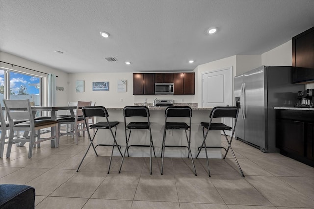 kitchen featuring a kitchen breakfast bar, recessed lighting, light tile patterned floors, visible vents, and appliances with stainless steel finishes