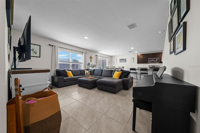 living area featuring visible vents, recessed lighting, light tile patterned flooring, and a textured ceiling