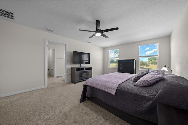 bedroom with ceiling fan, a textured ceiling, light colored carpet, visible vents, and baseboards