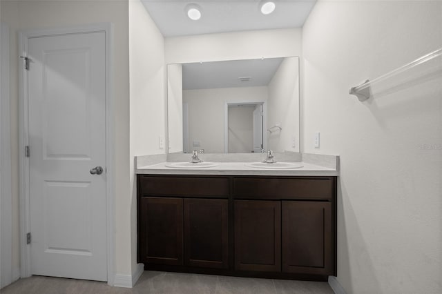 full bath featuring double vanity, baseboards, and a sink
