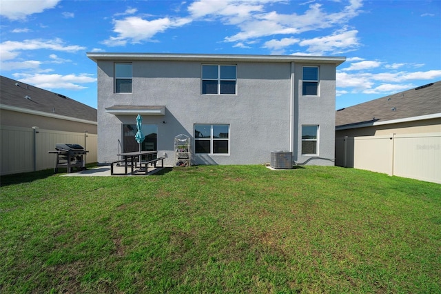 rear view of property with a lawn, stucco siding, a patio area, and central AC