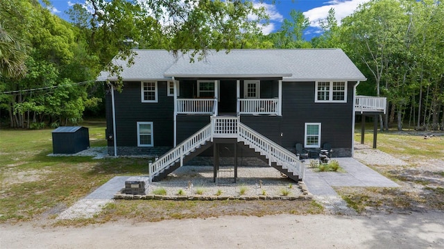 view of front of property featuring stairway, a front lawn, and covered porch