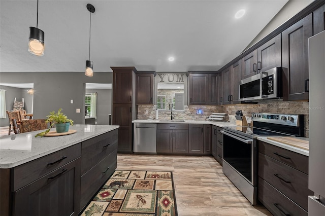 kitchen featuring tasteful backsplash, hanging light fixtures, a sink, dark brown cabinetry, and stainless steel appliances