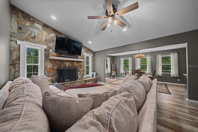 living room featuring baseboards, a fireplace, wood finished floors, ceiling fan with notable chandelier, and lofted ceiling