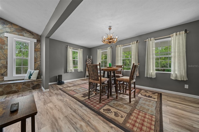 dining space featuring a chandelier, baseboards, and wood finished floors