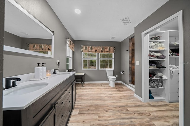 bathroom with toilet, wood finished floors, a sink, and visible vents