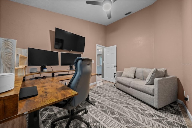 home office featuring visible vents, baseboards, a ceiling fan, and wood finished floors