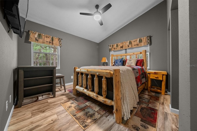 bedroom featuring wood finished floors, ceiling fan, baseboards, and lofted ceiling