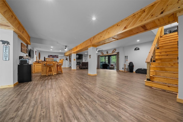 living area featuring stairs, ceiling fan, baseboards, and wood finished floors