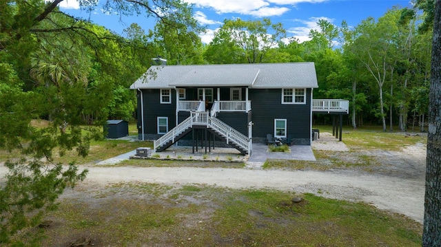 view of front facade with a chimney, driveway, an outdoor structure, and stairs