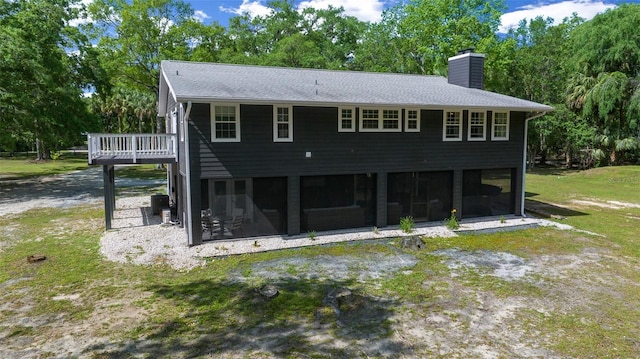 rear view of house with central air condition unit, a chimney, a shingled roof, a sunroom, and a lawn