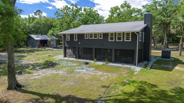rear view of property featuring a yard, a sunroom, and a chimney