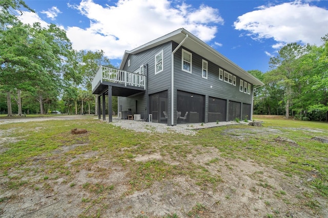 rear view of house with a sunroom, central AC unit, a deck, and a lawn