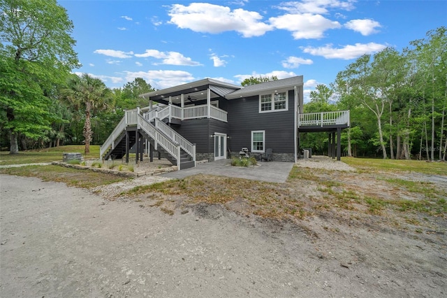 back of property featuring a patio, stairway, a deck, and stone siding