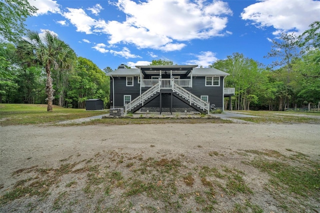 rear view of house with a chimney, a wooded view, and stairway