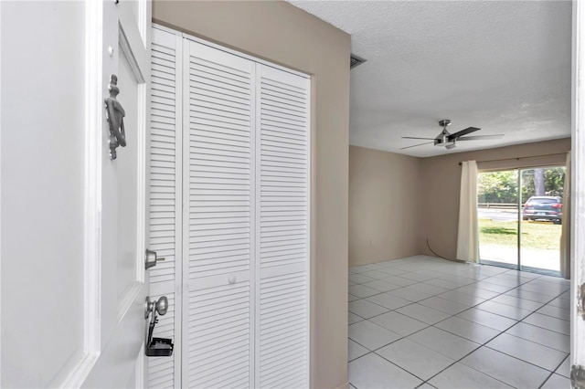 corridor featuring light tile patterned floors and a textured ceiling