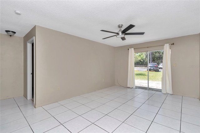 spare room featuring a textured ceiling, light tile patterned flooring, and a ceiling fan