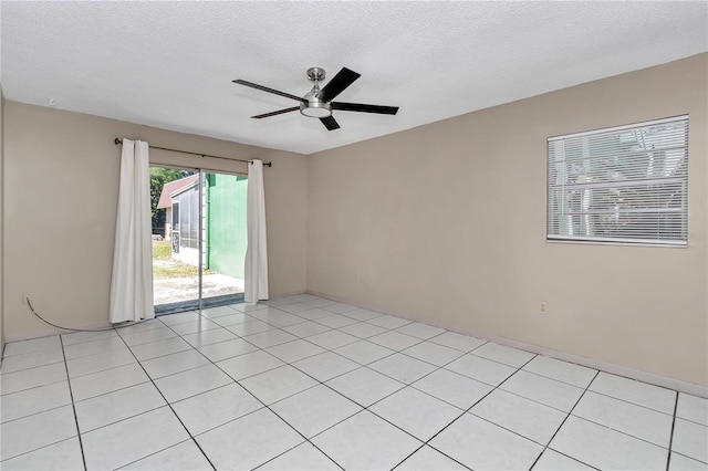 spare room with a textured ceiling, a ceiling fan, and light tile patterned flooring