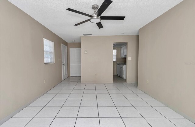 unfurnished room featuring light tile patterned floors, visible vents, a textured ceiling, and ceiling fan