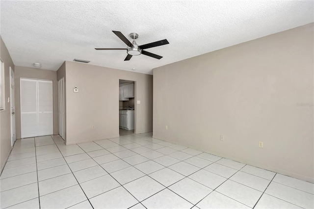 spare room featuring light tile patterned floors, a ceiling fan, visible vents, and a textured ceiling