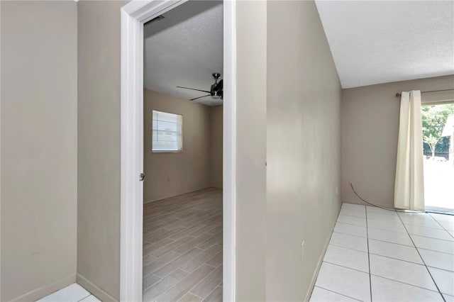 hallway featuring light tile patterned floors and a textured ceiling