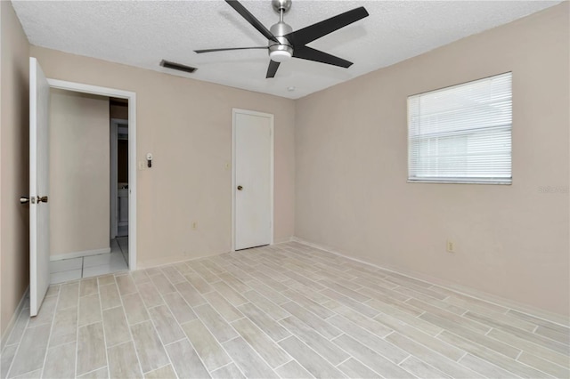 unfurnished bedroom with visible vents, a textured ceiling, and a ceiling fan