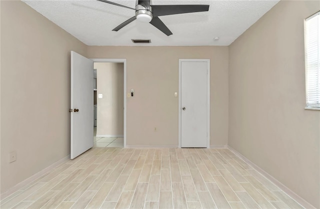 unfurnished room with visible vents, baseboards, ceiling fan, light wood-style floors, and a textured ceiling