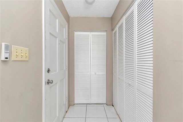 hall featuring a textured ceiling and light tile patterned flooring