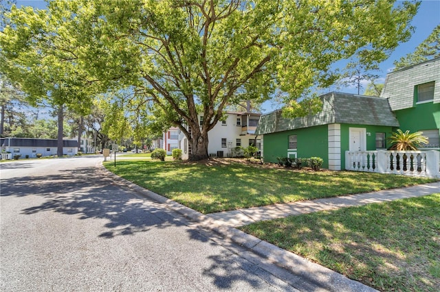 view of front facade featuring a front yard, roof with shingles, fence, and mansard roof