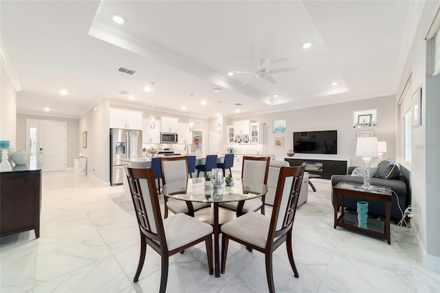 dining space with a ceiling fan, marble finish floor, a raised ceiling, ornamental molding, and visible vents