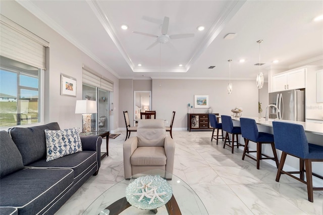 living area with a tray ceiling, recessed lighting, a ceiling fan, marble finish floor, and ornamental molding