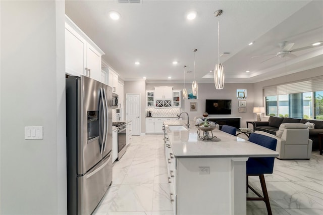 kitchen featuring marble finish floor, a breakfast bar, a sink, appliances with stainless steel finishes, and open floor plan