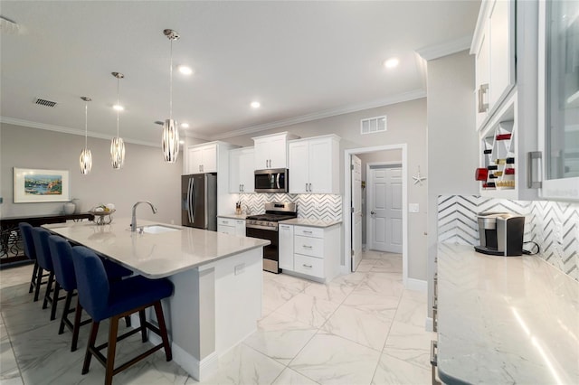 kitchen with a sink, visible vents, a kitchen bar, decorative backsplash, and appliances with stainless steel finishes