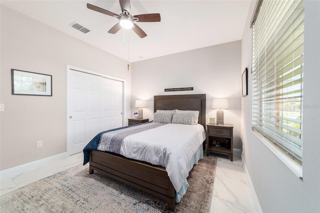 bedroom with a closet, visible vents, marble finish floor, and baseboards